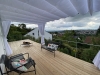 White waterproof Roman blind 3x4 m installed over a wooden terrace with outdoor furniture and a scenic view