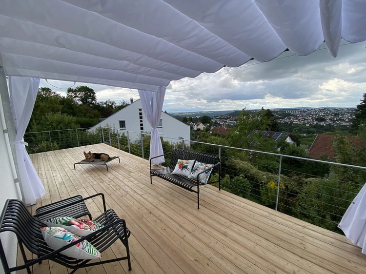 White waterproof Roman blind 3x4 m installed over a wooden terrace with outdoor furniture and a scenic view
