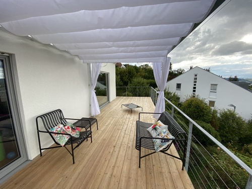 White 3x4 m premium waterproof Roman terrace blind providing shade over a modern wooden deck with outdoor seating