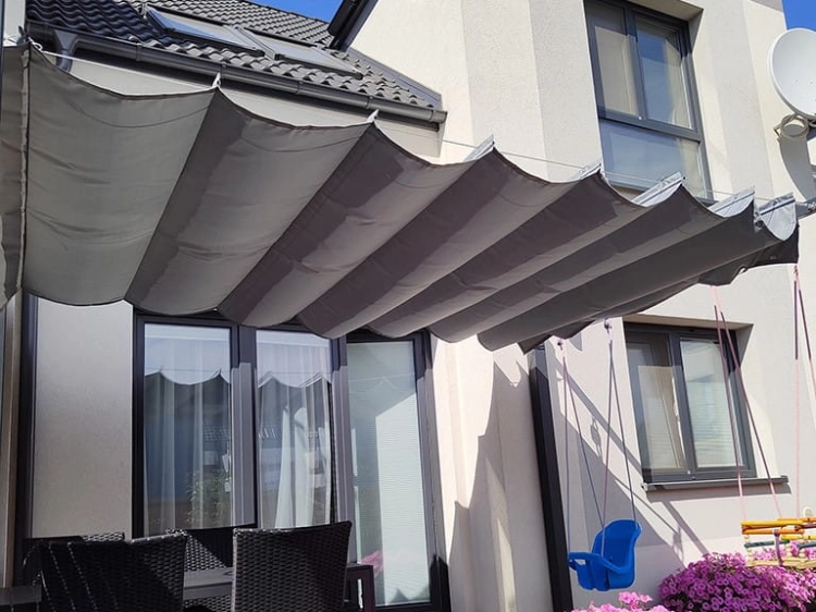 Grey waterproof 3x4 m retractable Roman awning provides shade over a home patio with outdoor furniture and a blue swing