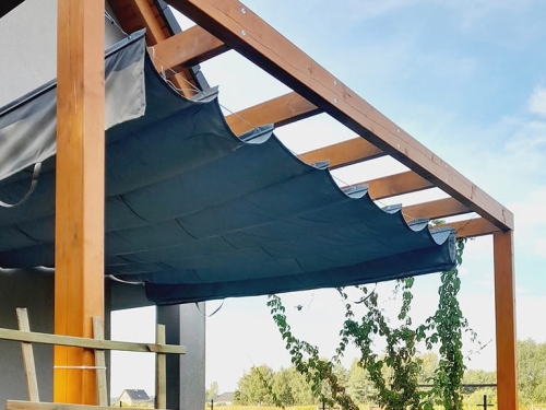 Grey retractable Roman patio shade sail installed on a wooden pergola for sun and rain protection.