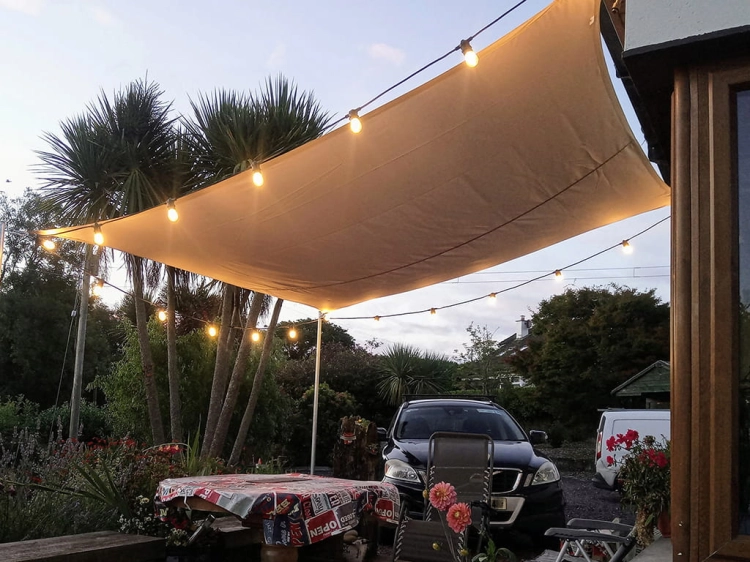 Waterproof square 4x4m garden shade sail in premium sand fabric with integrated outdoor string lights over a patio