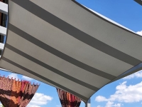 Grey and white striped waterproof rectangle sun shade sail installed outdoors against a blue sky.