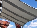 Graues Sonnensegel wasserdicht rechteckig als Sonnenschutz über der Terrasse vor blauem Himmel