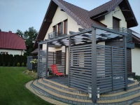 Grauer Sonnenschutzstreifen für Pavillons an einer Holzpergola bei einem modernen Einfamilienhaus montiert