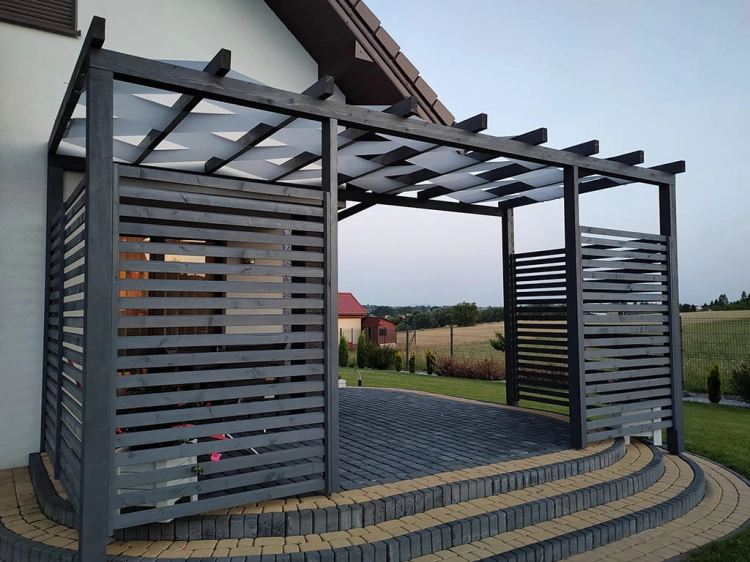 Dark wood garden pergola with a white sunshade weave over a brick patio with steps and horizontal privacy slats.