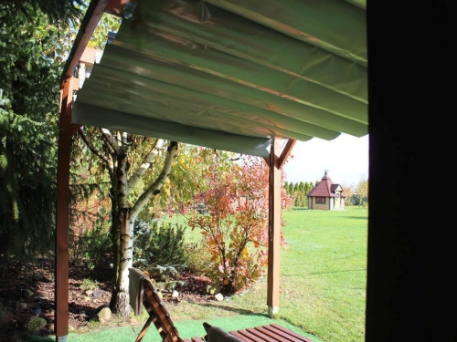Manual roman blind shade system with a retractable pulley mechanism installed on a wooden garden pergola structure.