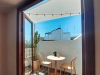 White waterproof balcony shade sail over a patio with a table, chairs, cafe moka pot, and a cactus in a pot