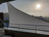White waterproof triangular sun shade sail installed on a city balcony for UV protection and privacy