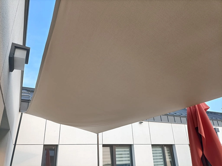 Beige waterproof custom-made sun shade sail mounted over a balcony terrace to provide shade and UV protection