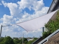 Weißes rechteckiges Sonnensegel für den Balkon, montiert an Masten am Dach mit Blick auf das Stadtpanorama