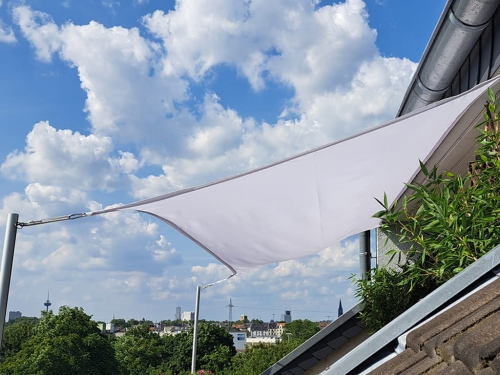White waterproof balcony sun sail shade custom-made for an outdoor terrace with city skyline views