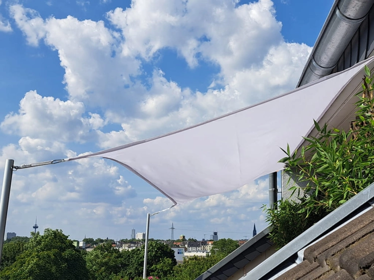 White waterproof balcony sun sail shade custom-made for an outdoor terrace with city skyline views