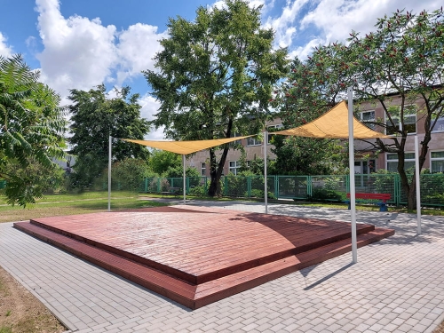 Triangular HDPE sun shade sail measuring 3x3x4.2m installed over a wooden garden platform with white mounting poles