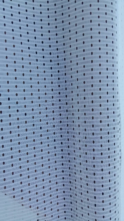 White mesh patio curtain fabric with a small perforated dot pattern in vertical rows.