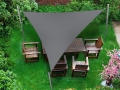 Graues Premium Sonnensegel dreieckig über Gartenmöbeln aus Holz auf grünem Rasen