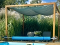 Wasserdichtes, ausziehbares Sonnensegel 3x3 m Premium in Meeresblau, montiert auf einer Holzpergola über dem Pool