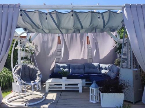 Premium waterproof 3x5 m grey retractable shade sail over a white pallet cozy patio lounge with a swing chair