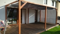 Grijs, waterdicht gordijn op maat als overkapping en zijwand voor een houten pergola op het terras