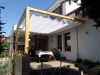 White retractable roman shade installed on a wooden terrace pergola for sun protection and waterproof outdoor comfort.