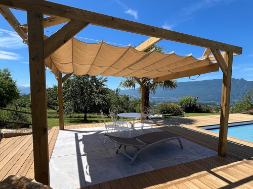 Beige retractrable roman patio canopy 3x4m on a wooden pergola overlooking a garden and mountains