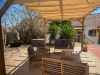 Beige roman sunshade mounted on a wooden garden pergola over outdoor patio furniture on a wooden deck