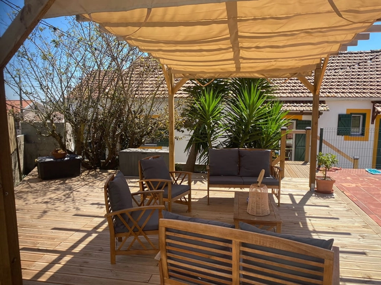 Beige roman sunshade mounted on a wooden garden pergola over outdoor patio furniture on a wooden deck