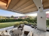 Retractable terrace roman blind providing shade over a modern patio with comfortable lounge furniture and garden view