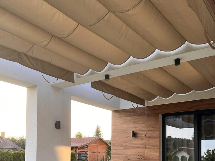 Beige 3x4 m waterproof patio Roman blind provides shade under a white pergola with outdoor lighting.