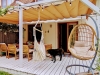 Retractable waterproof Roman shade canopy over a patio with outdoor furniture, a hanging chair, and a dog