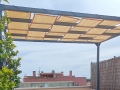 Beigefarbene Pavillonstreifen aus HDPE-Gewebe an einer Metall-Terrassenpergola als Schattenspender