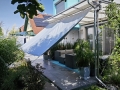 Lichtgrijs waterdicht tuingordijn op maat gemonteerd op een terras als zon- en regenwering