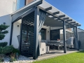 Modernes Sonnensegel für den Garten, wasserdicht, nach Maß unter einer dunklen Terrassenpergola montiert