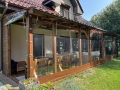 Custom-made transparent terrace tarp screens fixed to a wooden porch with chairs and tables visible inside.