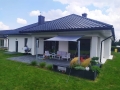 Graues Sonnensegel wasserdicht montiert über der Terrasse eines modernen Einfamilienhauses