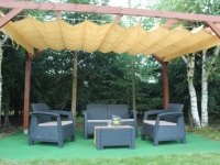 Tenda a pacchetto parasole beige in HDPE montata su una pergola in legno sopra un set di mobili da giardino