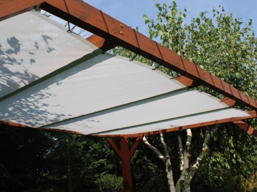 Weißes Sonnensegel montiert an einer Holzpergola im Garten