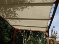 Egyedi méretű fehér HDPE napvitorla kerti fa pergolára szerelve, amely kellemes árnyékot ad