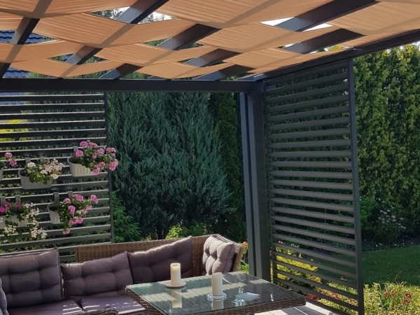 Custom waterproof sunshade sail woven through a modern gray metal pergola over an outdoor patio seating area.