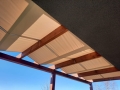 Wasserdichte römische Lamelle als Sonnenschutz, unter der Holzkonstruktion einer Maẞ-Terrassenpergola montiert