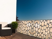 Protezione economica per balcone con stampa di tronchi d'albero montata sulla ringhiera del terrazzo contro una parete bianca
