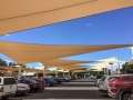 Maßgefertigte beige Sonnensegel über einem Parkplatz zum Schutz der Autos vor der Sonne