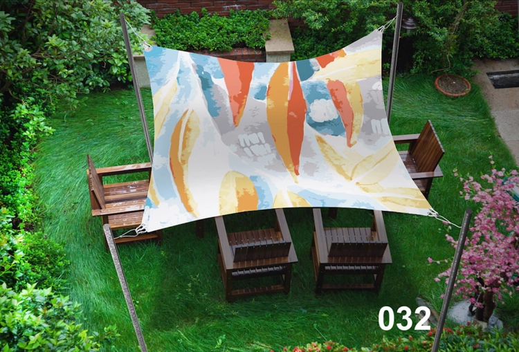 Custom printed sun shade sail over a wooden garden patio set surrounded by green grass and trees.