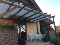 Weiße Sonnensegel nach Maß montiert an einer Holzpergola über der Terrasse mit Gartenmöbeln
