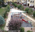 Weißes dreieckiges Sonnensegel über einem Sandkasten auf einem Spielplatz zwischen Wohnblöcken montiert