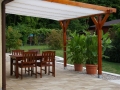 Weißes ausziehbares Sonnensegel 2,5x5 m montiert auf einer Holzpergola über einem Terrassenmöbel-Set