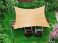 Rechthoekig zandkleurig HDPE schaduwdoek 3x4 m boven houten tuinmeubelen op het gazon