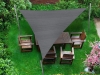Grey triangular shade sail made of HDPE fabric over a wooden garden furniture set on a green lawn.