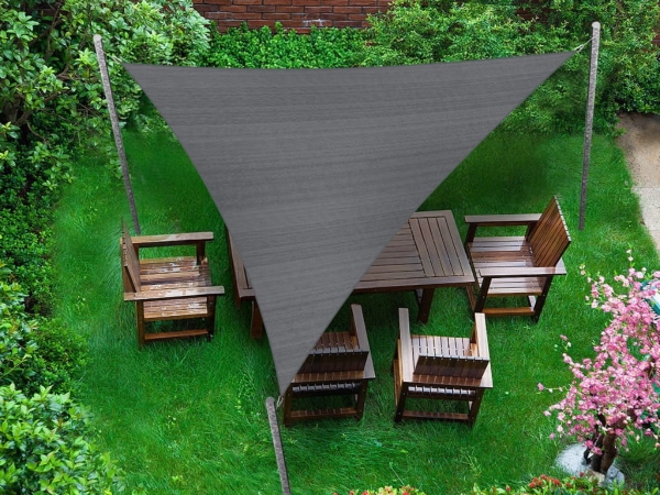 Sivá trojuholníková tieniaca plachta 4,2x4,2x5,9 m nad dreveným záhradným nábytkom na trávniku