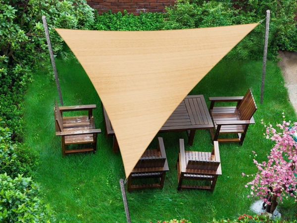 Triangular HDPE shade sail measuring 5x5x7m providing sun protection over a garden furniture set on a lawn